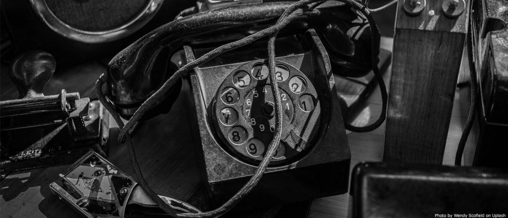 Rotary dial telephone on a table with wires and tools.